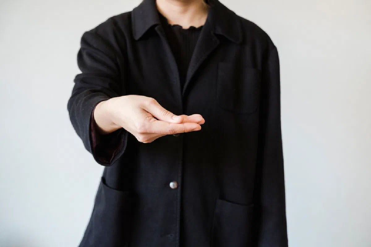 A close-up of an outstretched hand gesture in a studio setting with a white background.