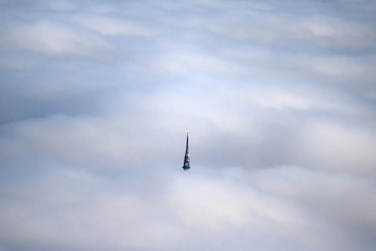 A breathtaking aerial shot of Le Mont-Saint-Michel's spire emerging above the cloud cover in Normandie, France.