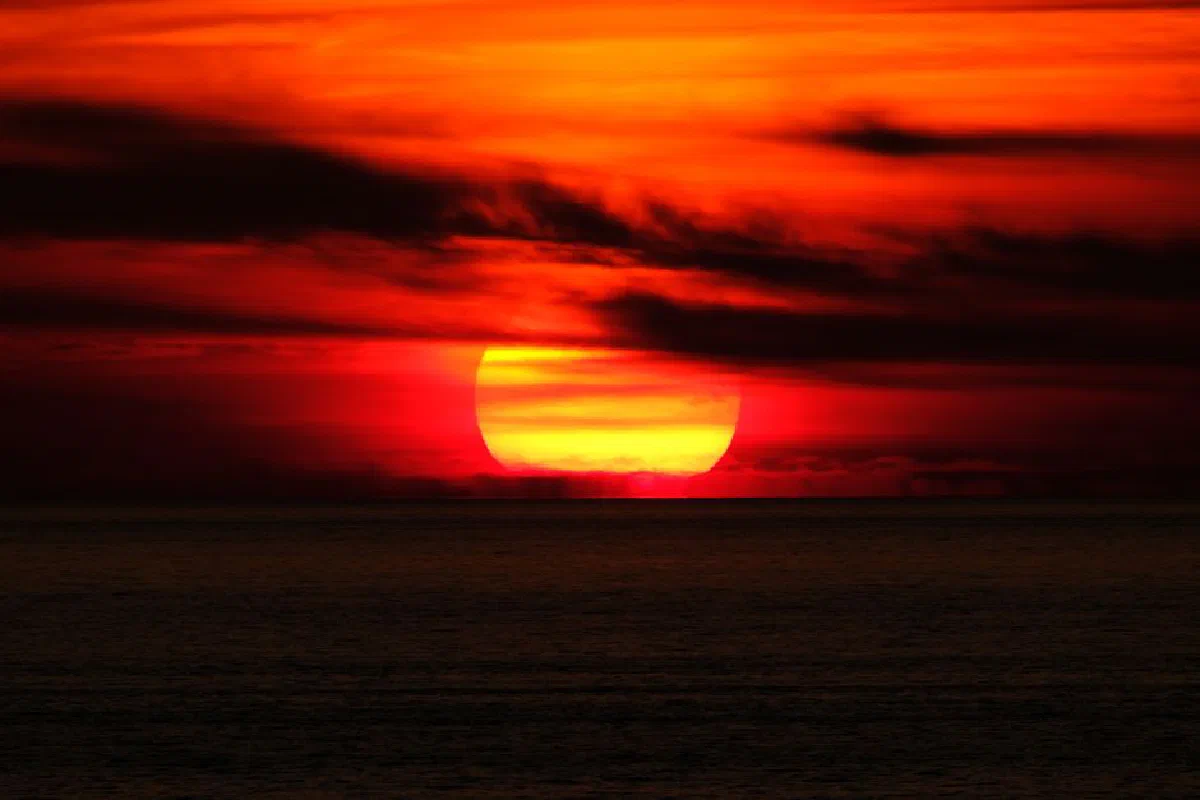 A stunning ocean sunset with vibrant red and orange hues illuminating the sky.