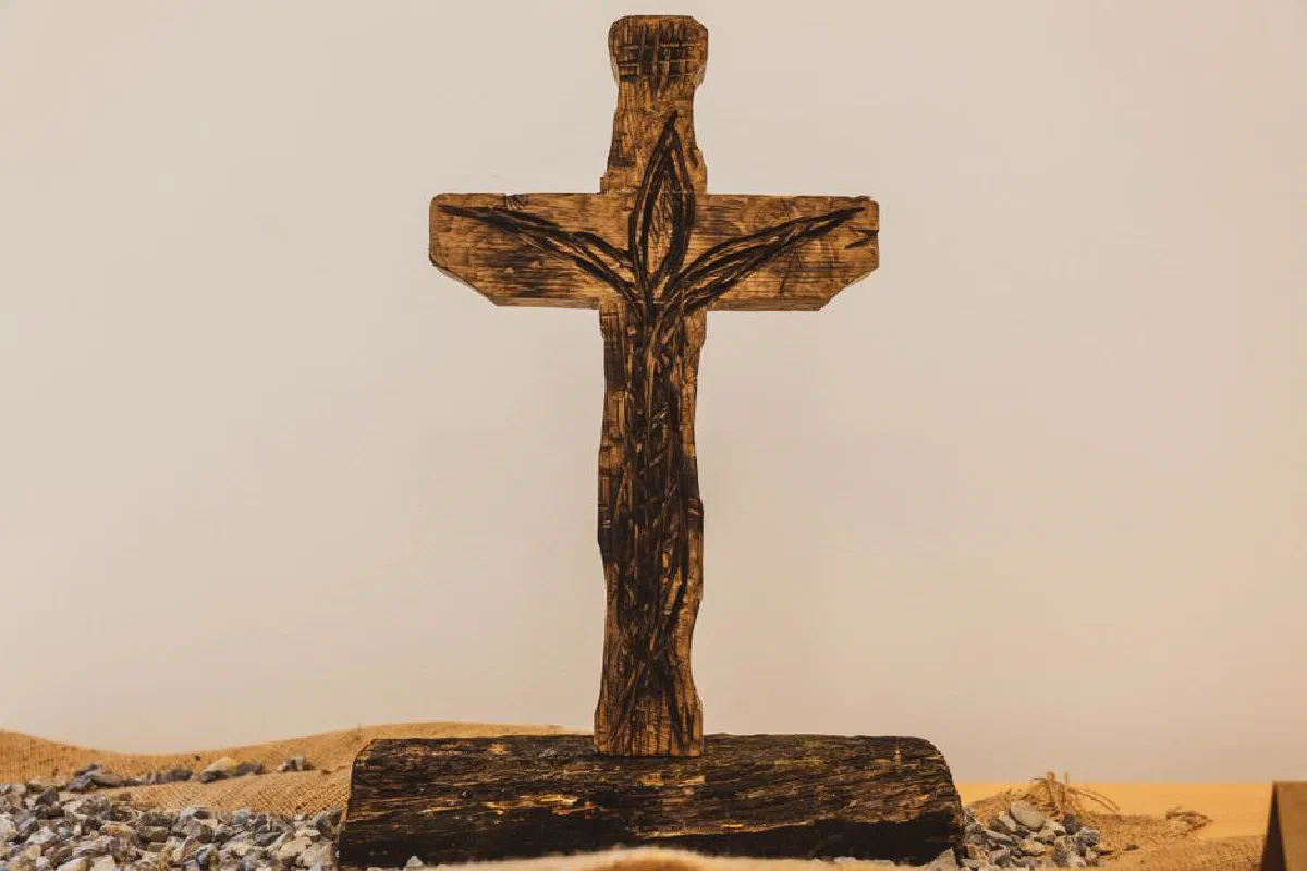 A beautifully crafted wooden cross with intricate designs in a serene museum setting.