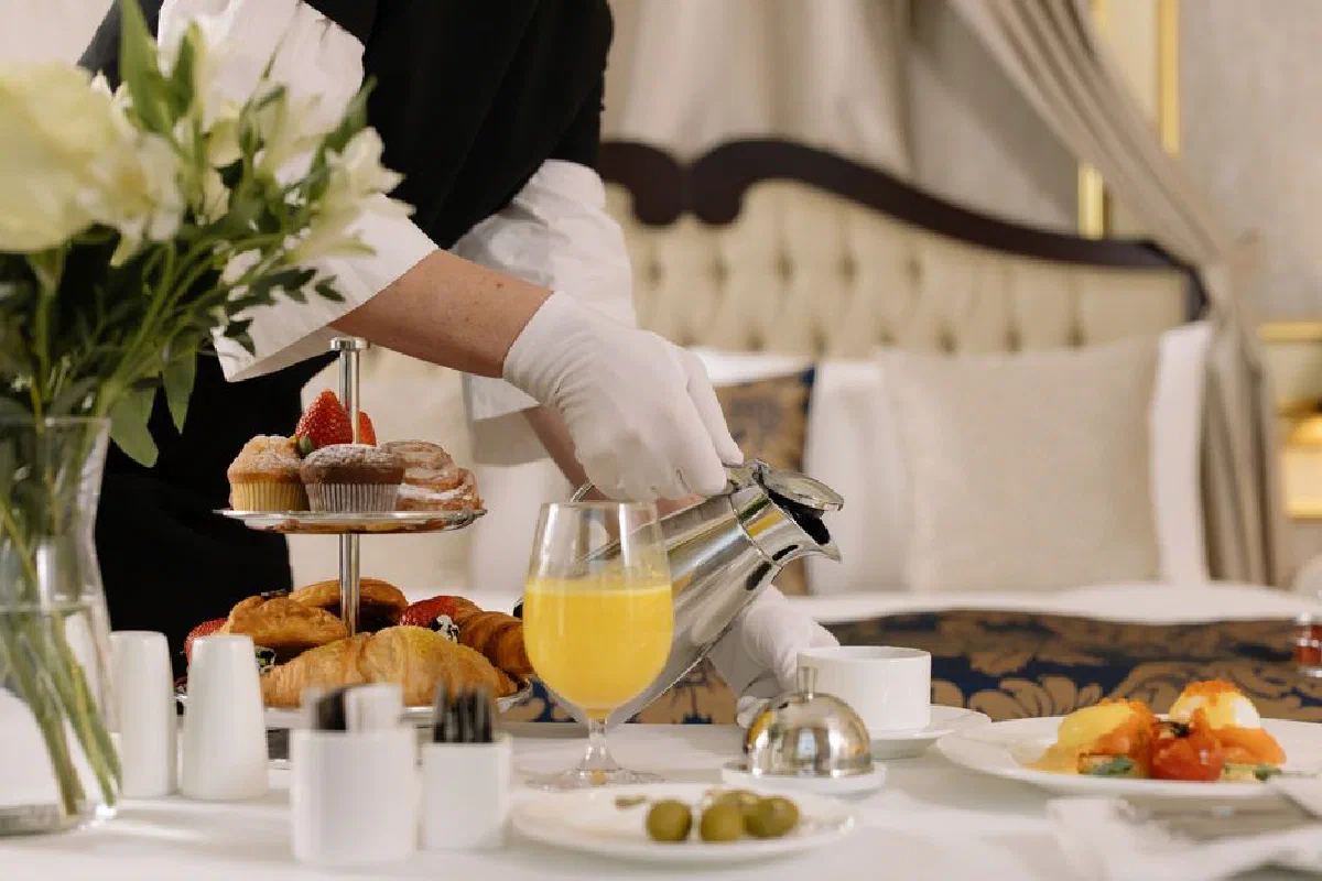 A stylish room service breakfast setup with pastries, coffee, and orange juice in a hotel room.