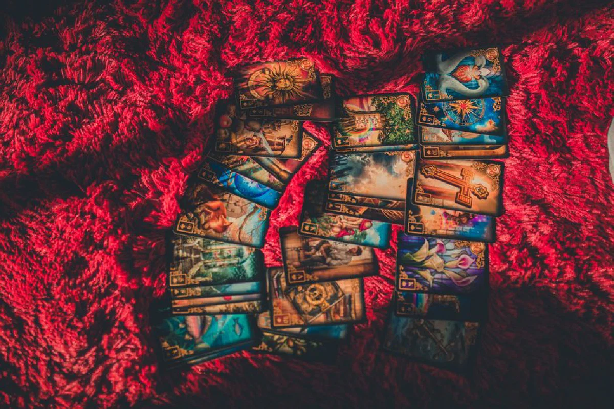 A collection of tarot cards laid out on a textured red fabric, evoking mystical and fortune-telling themes.