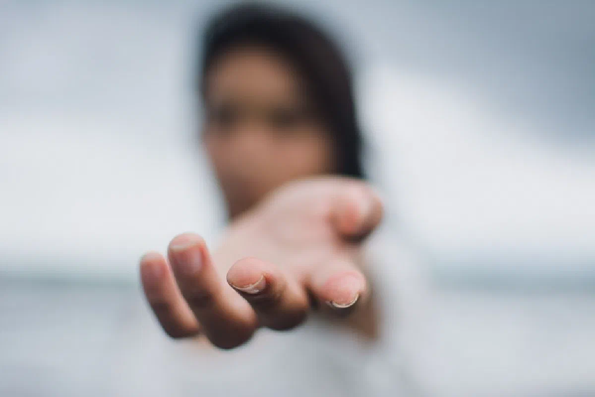 A soft focus image highlighting a reaching hand, symbolizing connection or help.