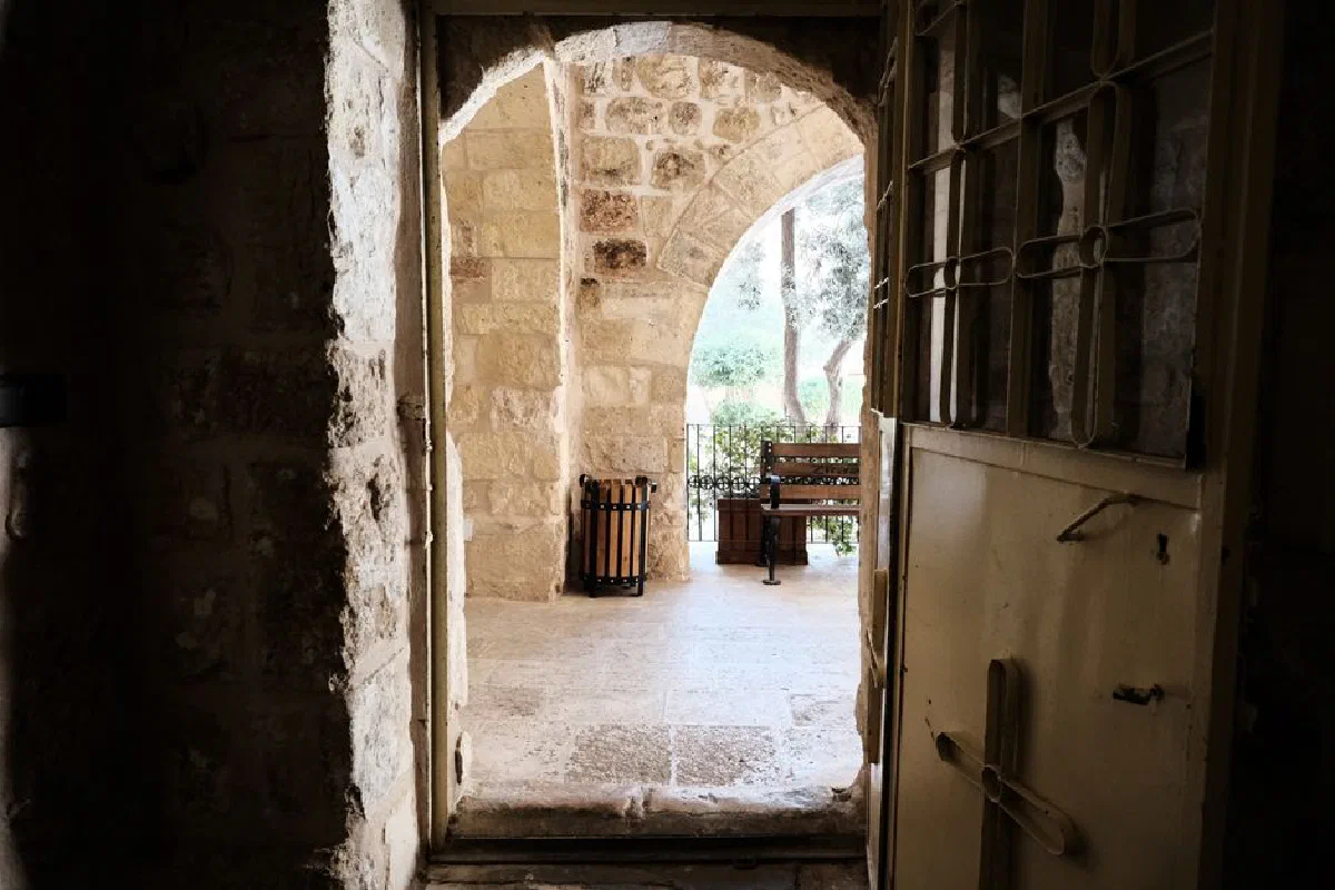 Looking through a stone archway to a serene courtyard with a bench and greenery, creating a peaceful ambiance.
