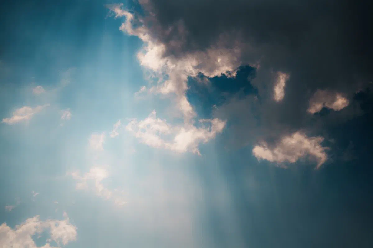 Sunlight streaming through dramatic clouds in the sky above Kyoto, Japan, creating a moody scene.