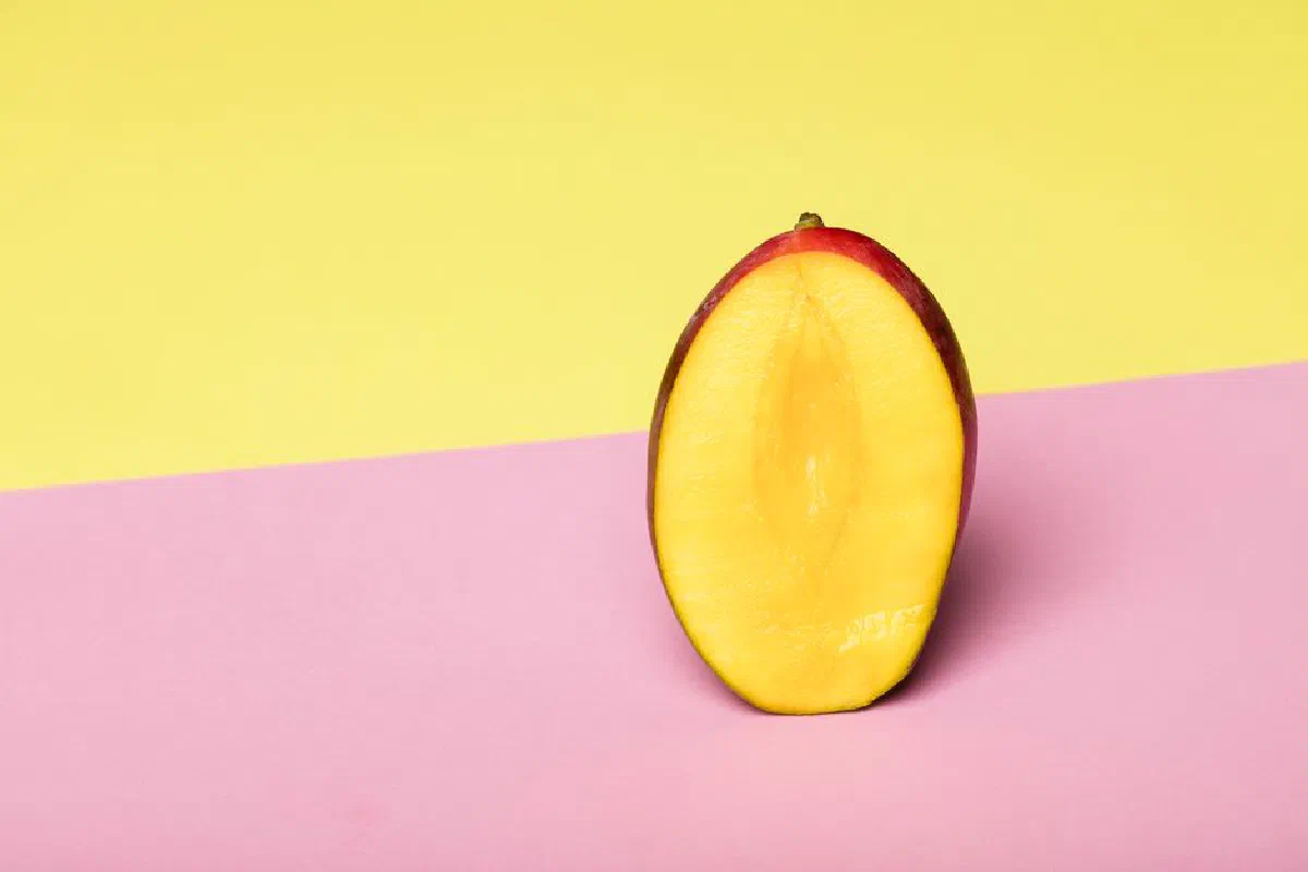 Fresh sliced mango on vibrant yellow and pink background, showcasing healthy food styling with copy space.