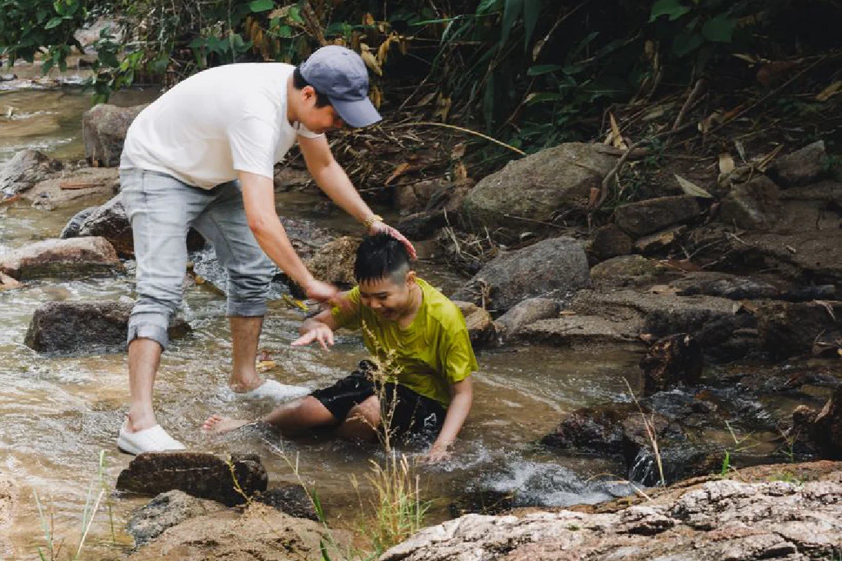 A father helping his son in a creek in Kon Tum, Vietnam, creating bonding moments outdoors.