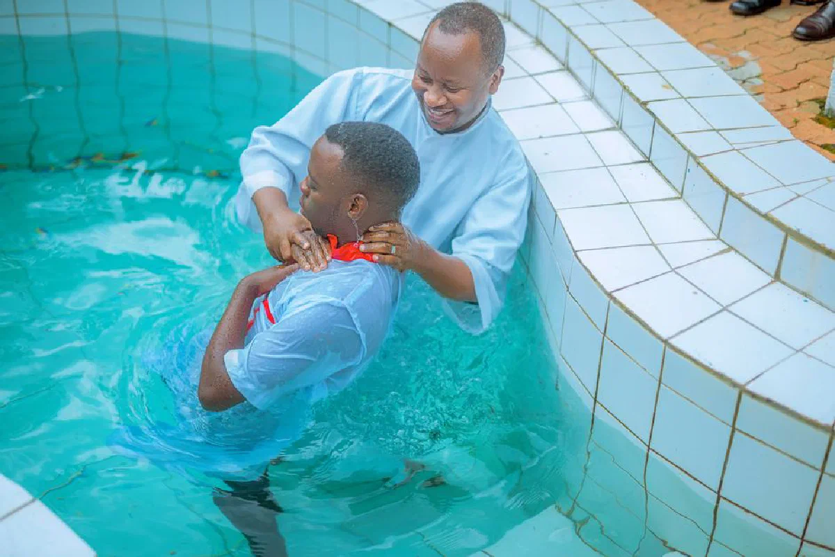 A man performing a baptism in a turquoise pool, signifying faith and spirituality.
