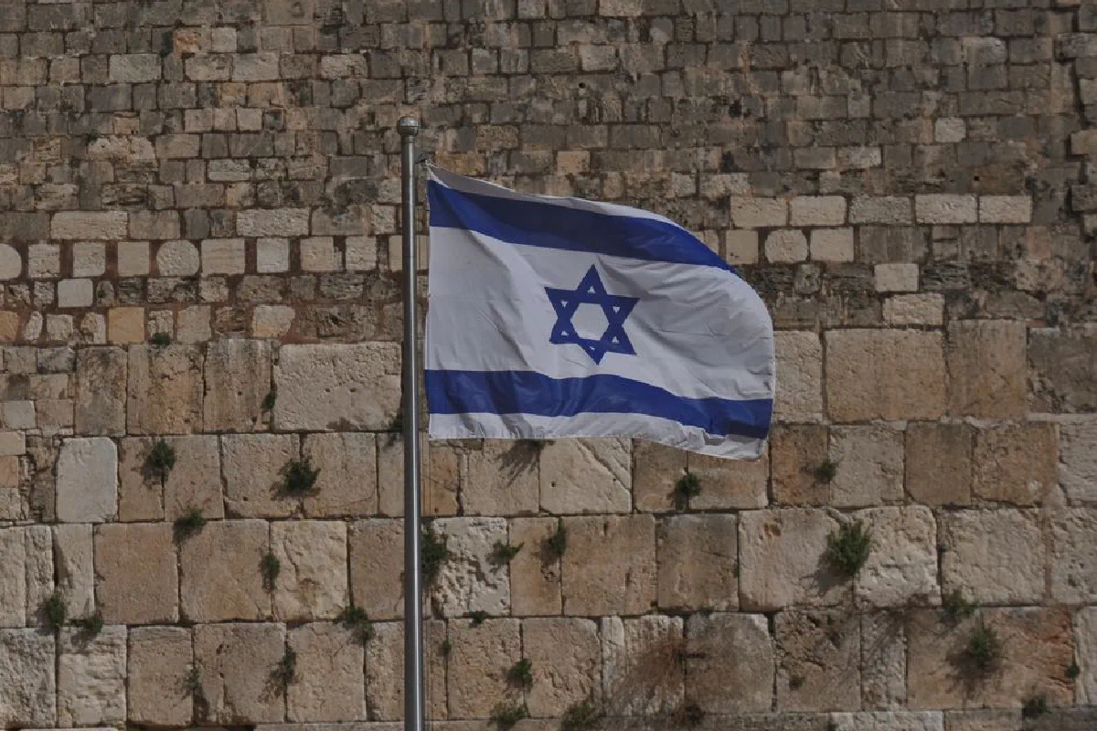Israeli national flag waving at the historic Western Wall in Jerusalem.
