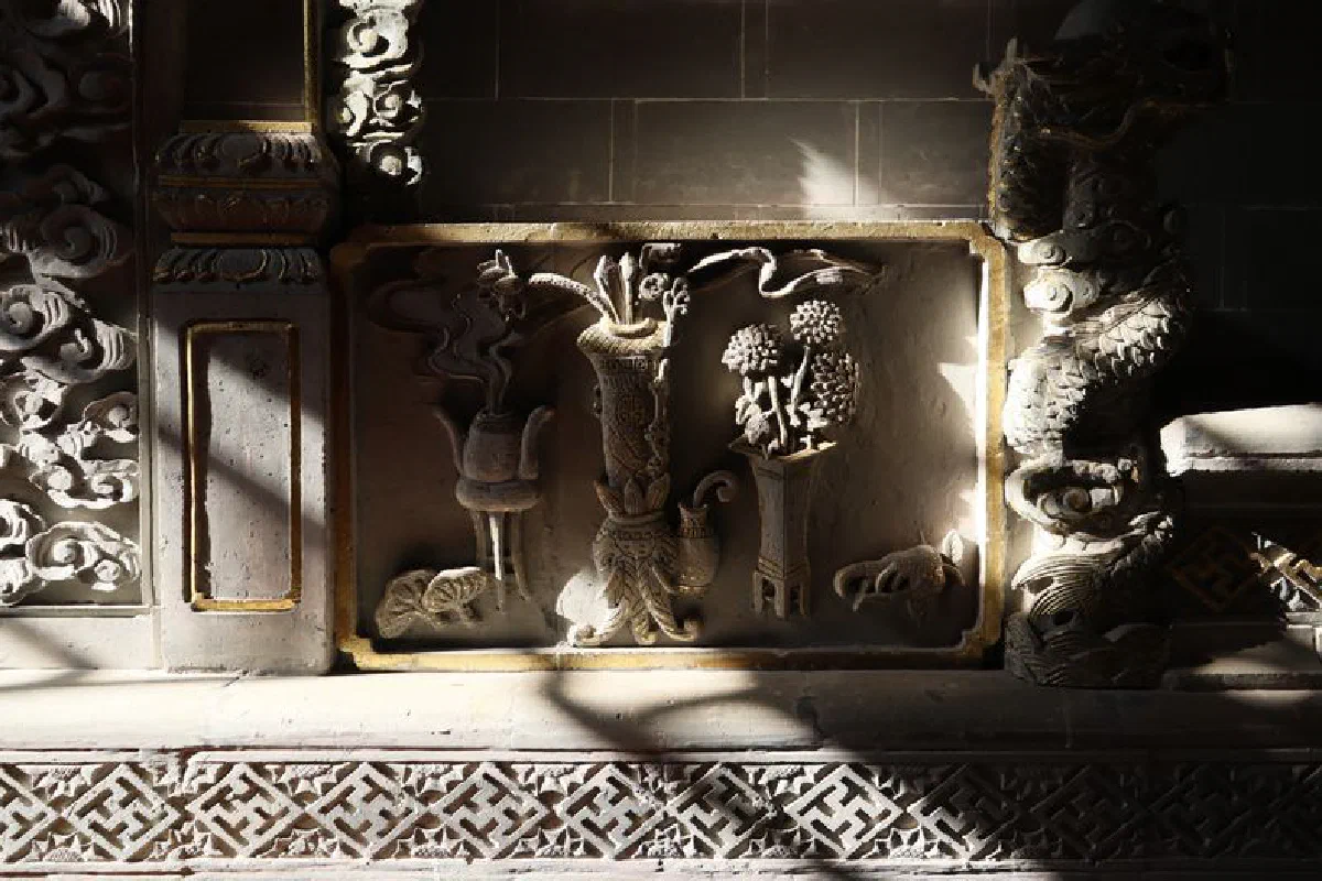 Intricate stone carving with floral and dragon motifs illuminated by sunlight in a temple.