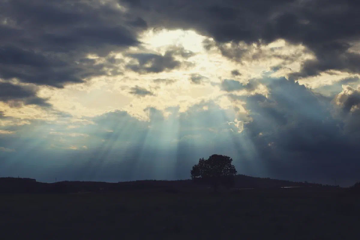 Sunlight breaks through dramatic clouds creating a picturesque landscape scene.