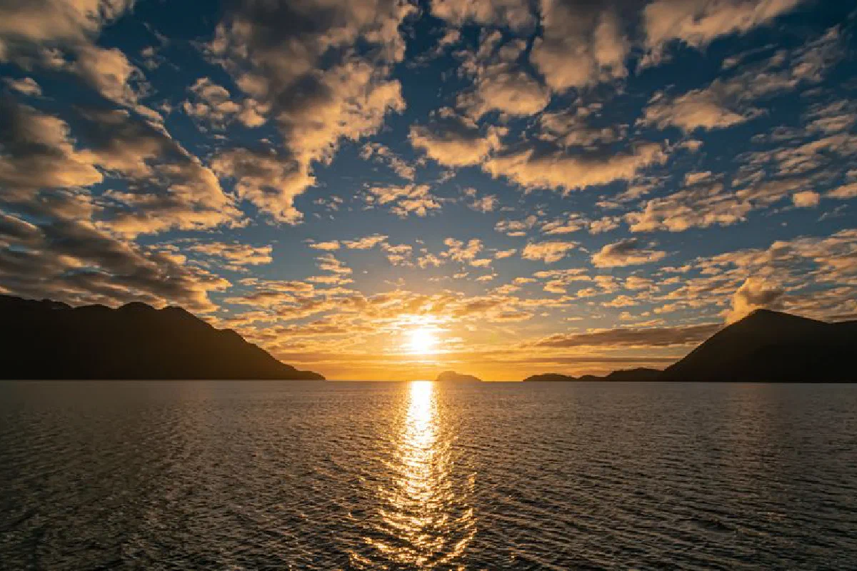 Breathtaking sunset over the ocean with stunning cloudscape and silhouette mountains.