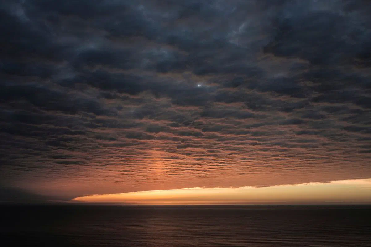 A breathtaking sunset over the ocean with dramatic clouds and vibrant colors.