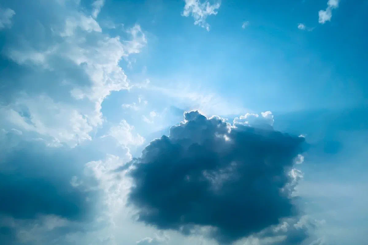Vibrant blue sky with dramatic cloud formations and sunlight peeking through in Gurugram, India.