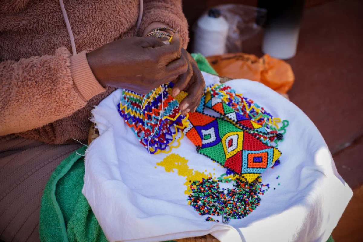 Close-up of a person creating vibrant beaded art with intricate patterns.
