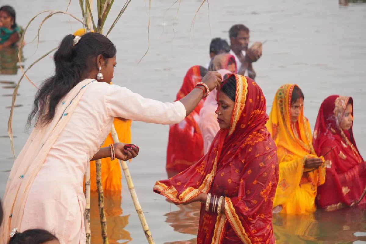 Women in vibrant sarees performing a religious ritual in the river.